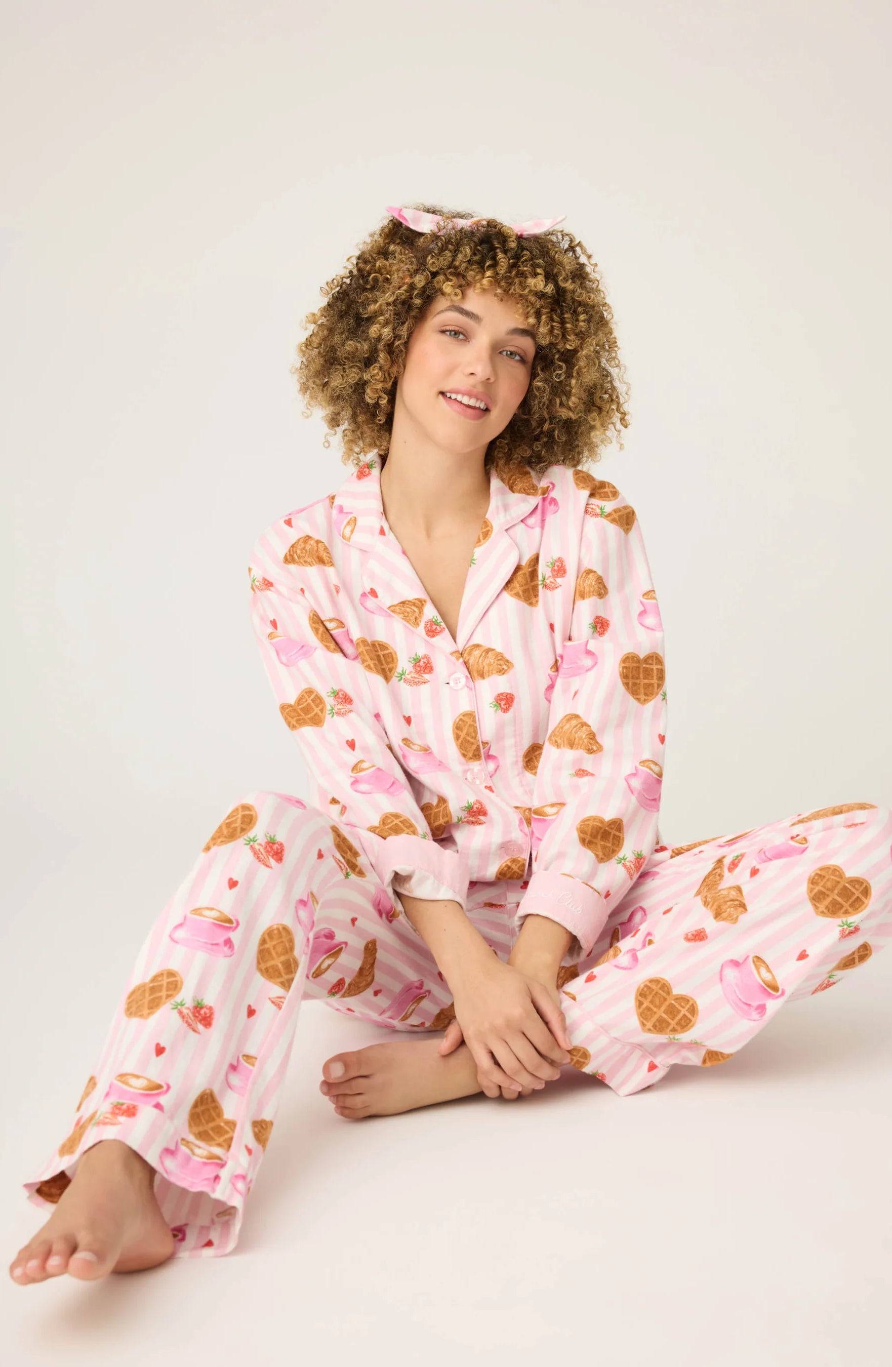 Woman wearing pink pajamas with heart patterns on a white background