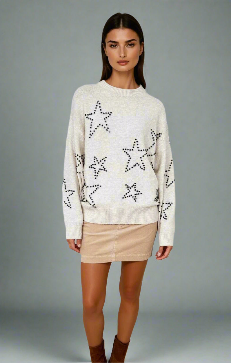 Woman wearing a cream sweater with star patterns on a white background