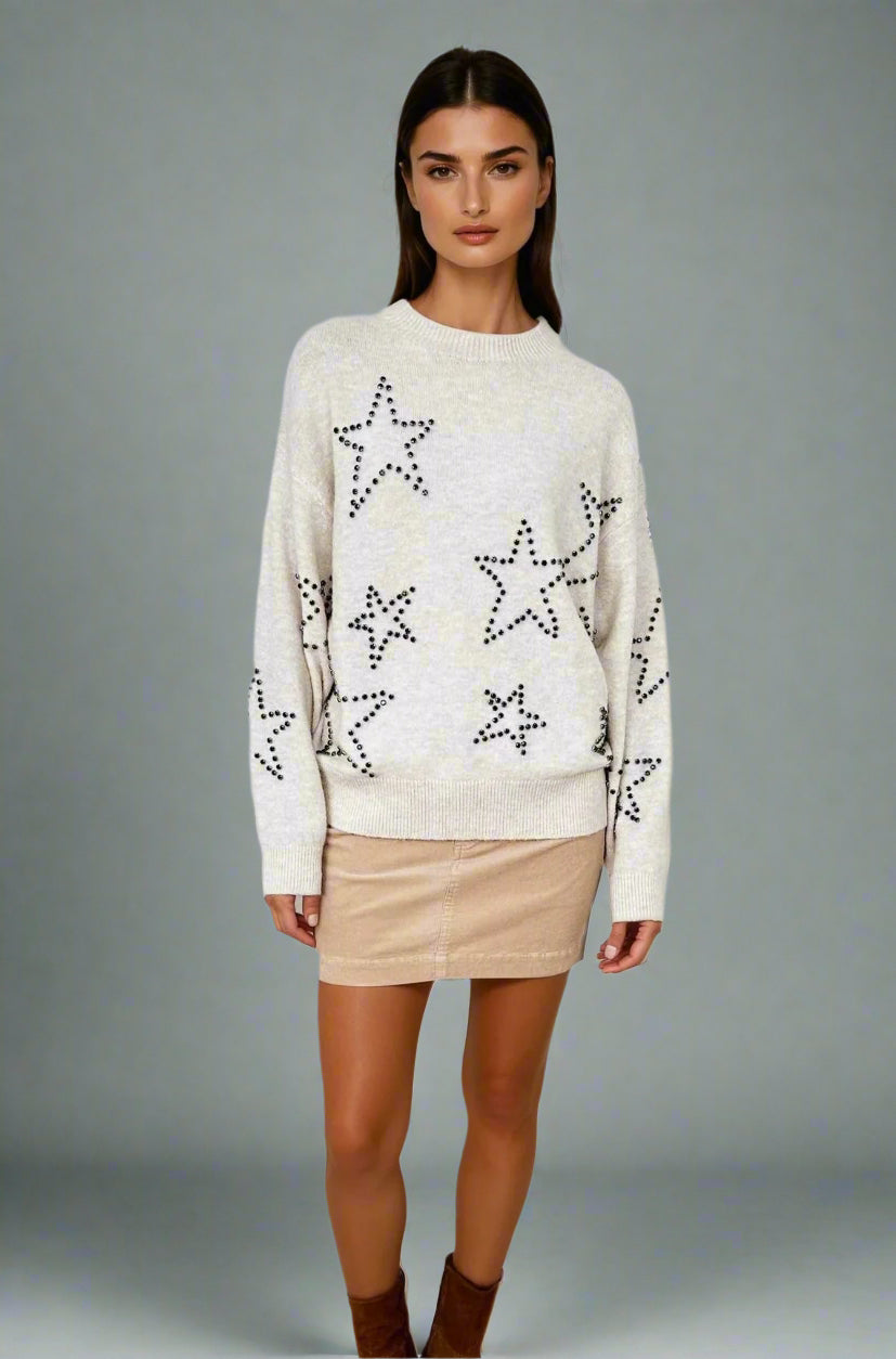 Woman wearing a cream sweater with star patterns on a white background