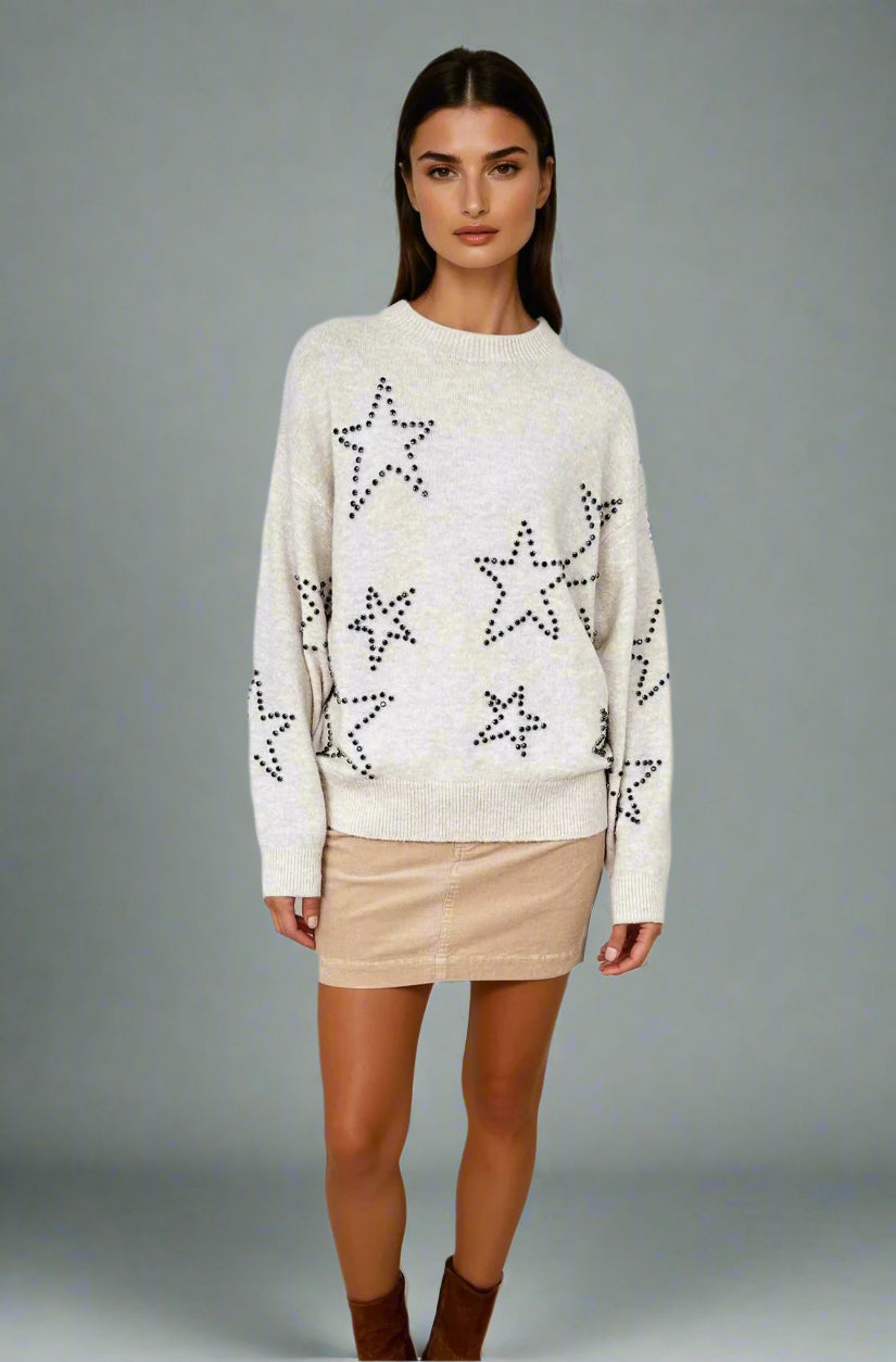 Woman wearing a cream sweater with star patterns on a white background