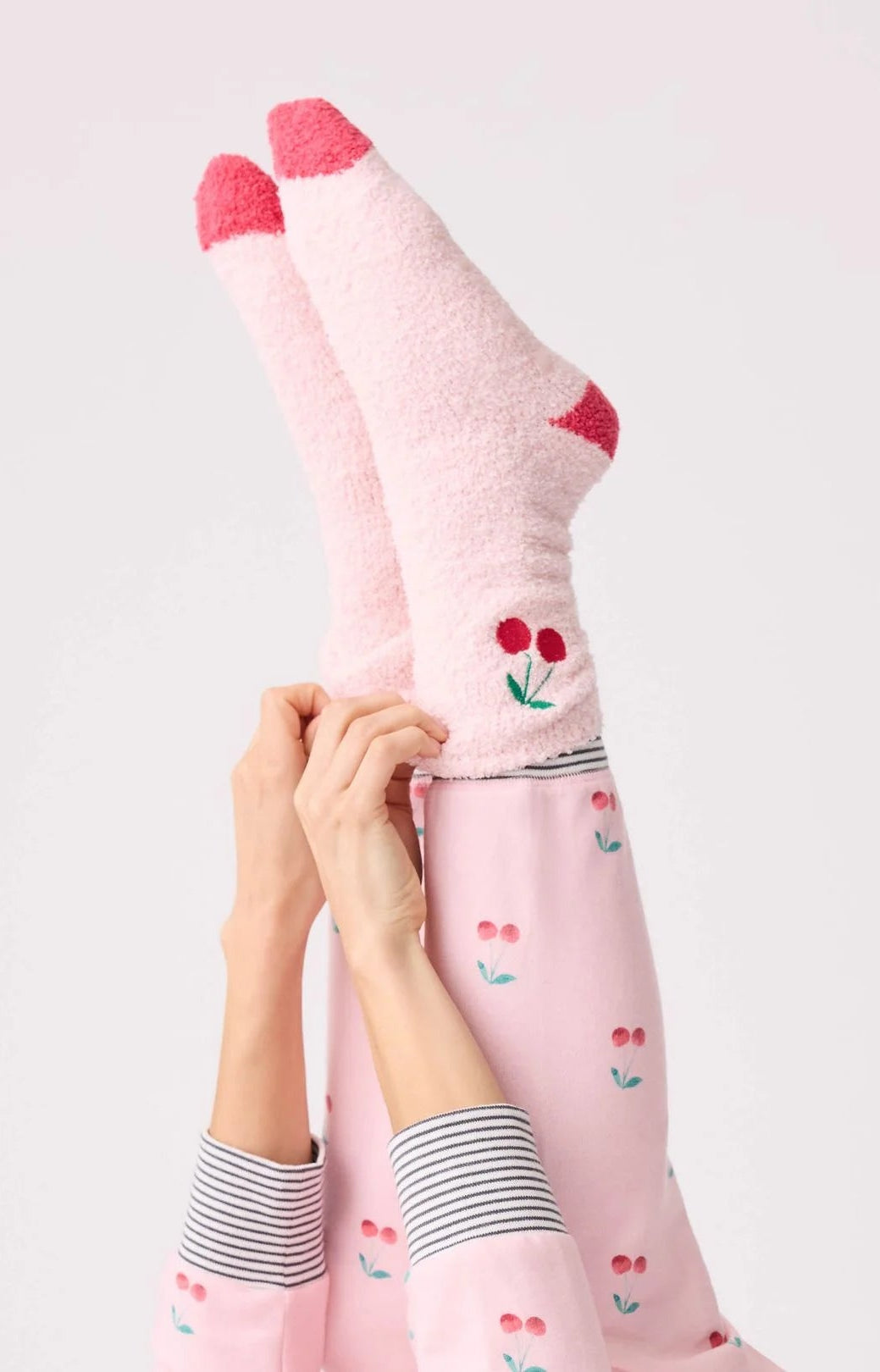 Person wearing pink socks with cherry design on a light gray background