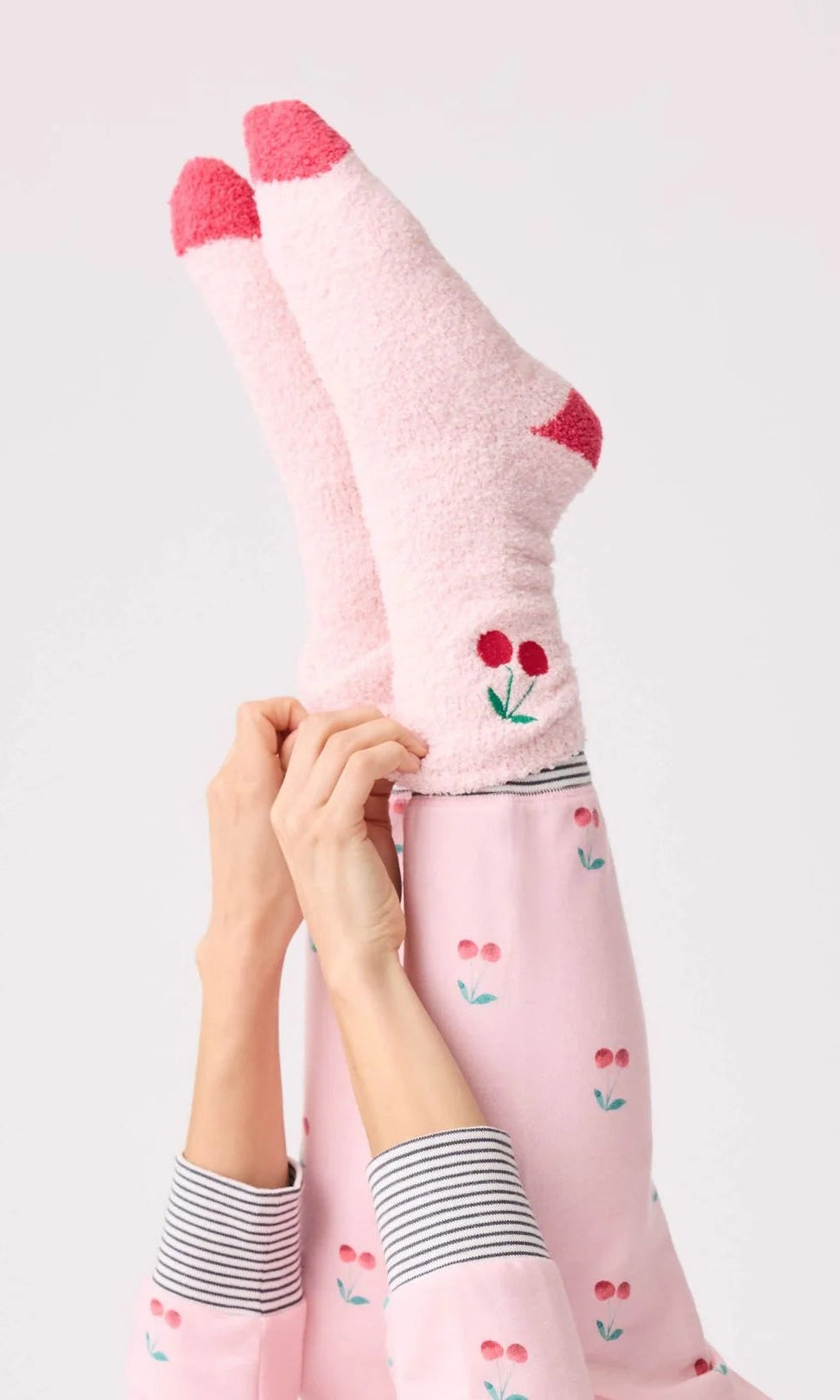 Person wearing pink socks with cherry design on a light gray background