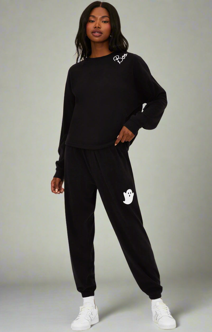 Person wearing a black tracksuit with a logo on a white background