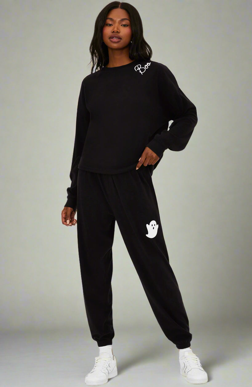 Person wearing a black tracksuit with a logo on a white background
