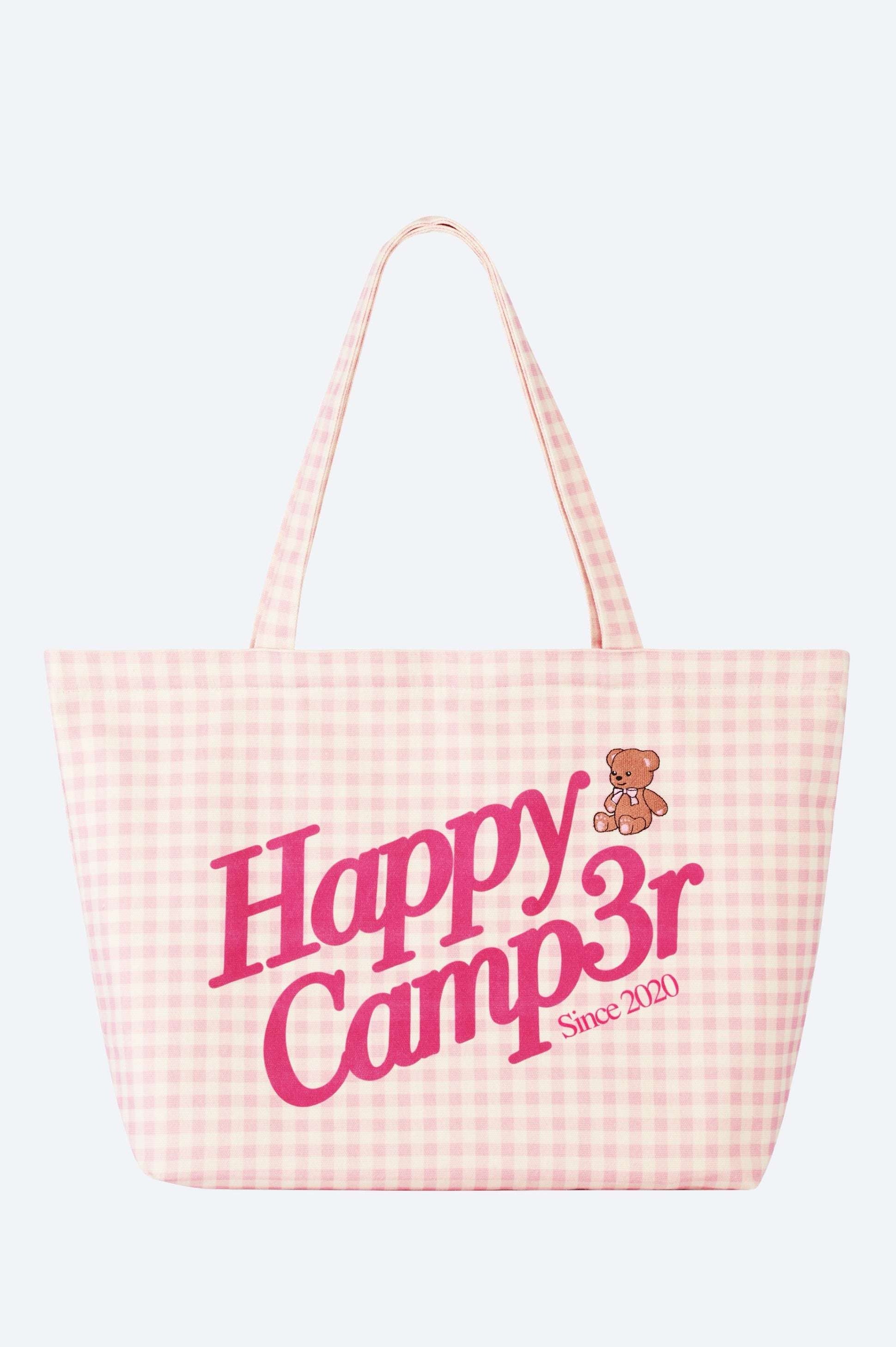 Pink checkered tote bag with 'Happy Camper' text and teddy bear graphic on a white background