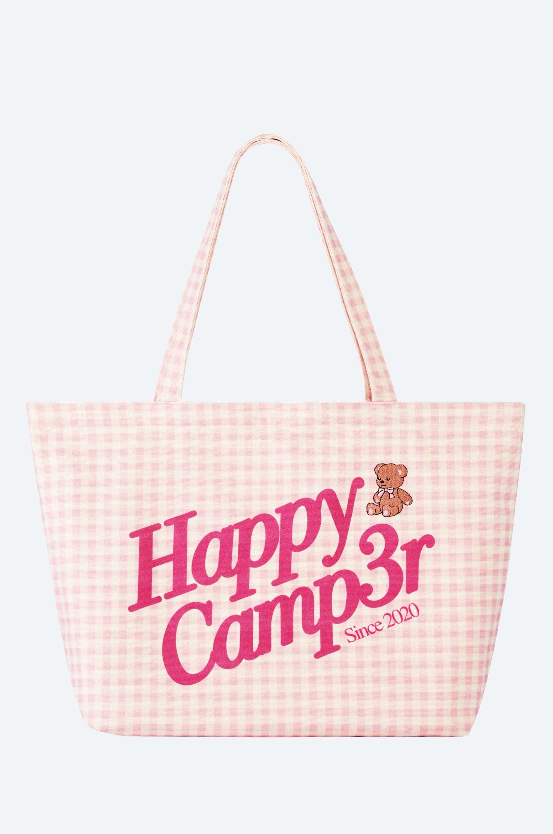 Pink checkered tote bag with 'Happy Camper' text and teddy bear graphic on a white background