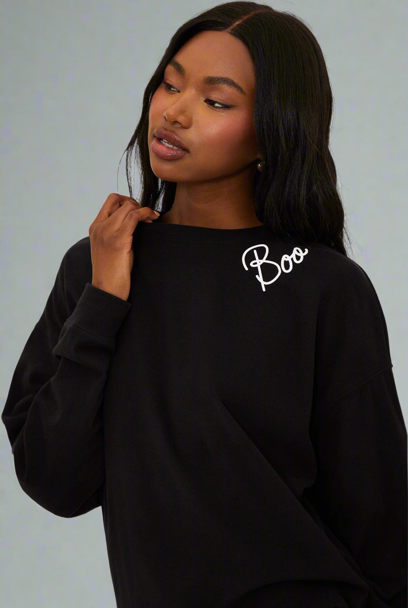 Person wearing a black sweatshirt with 'Boo' text on a white background