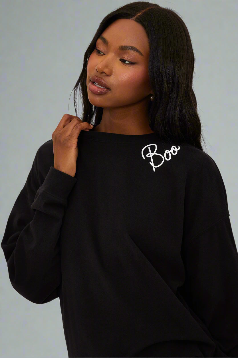 Person wearing a black sweatshirt with 'Boo' text on a white background
