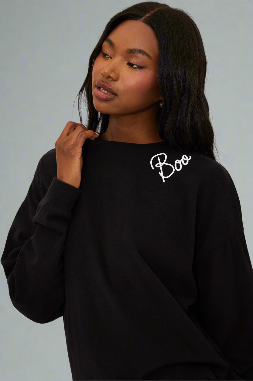 Person wearing a black sweatshirt with 'Boo' text on a white background