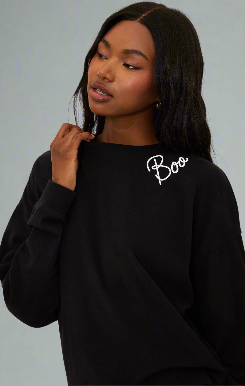 Person wearing a black sweatshirt with 'Boo' text on a white background