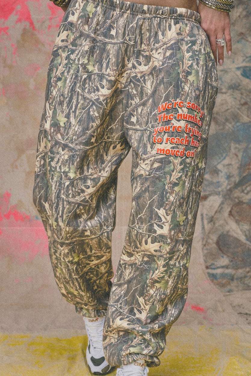 Camouflage pants with red text on a textured wall background