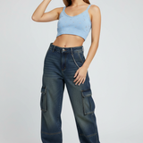 Woman wearing a light blue crop top, dark blue cargo pants, and a red cap on a white background