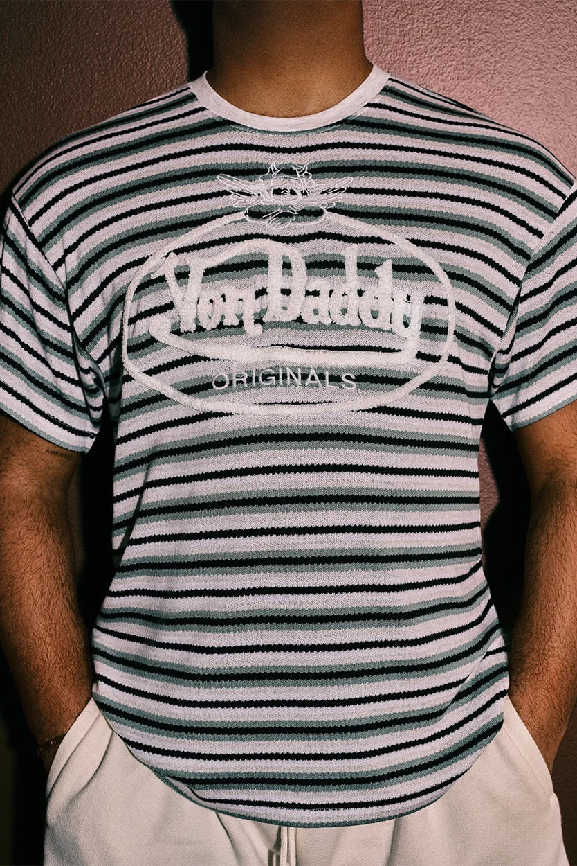 Person wearing a striped t-shirt with 'Von Daddy Originals' logo against a plain background