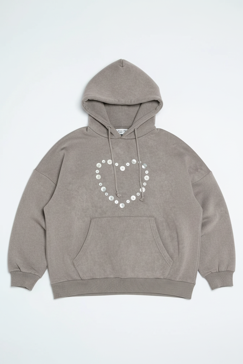 Woman wearing a gray hoodie and pants with decorative elements on a white background