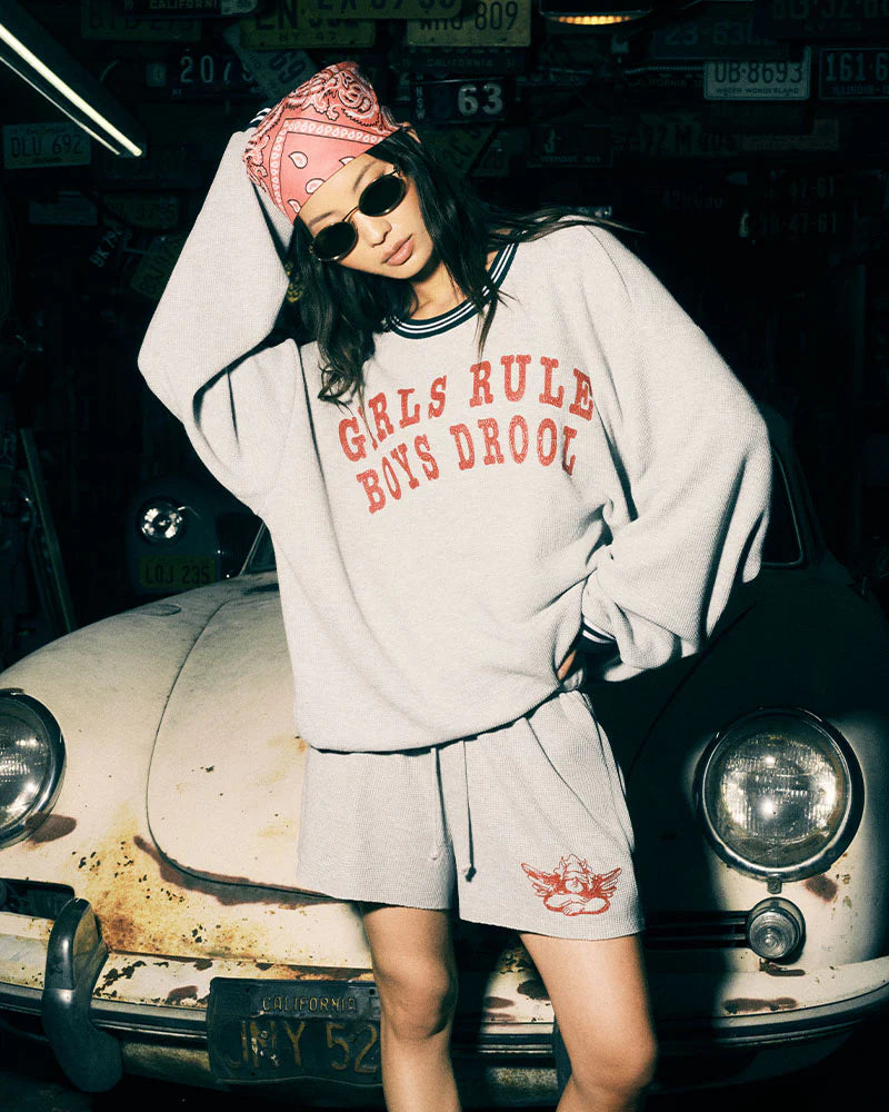 Person wearing a 'Girls Rule Boys Drooo' sweatshirt in front of a vintage car.