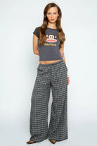 Woman wearing a Paul Frank t-shirt and checkered pants on a white background