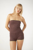 Woman wearing a strapless top and shorts with a subtle pattern on a white background