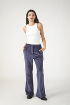 Woman wearing a white sleeveless top and blue pants on a white background