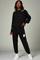 Person wearing a black tracksuit with a logo on a white background
