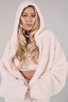 Person wearing a fluffy pink hoodie against a gray background